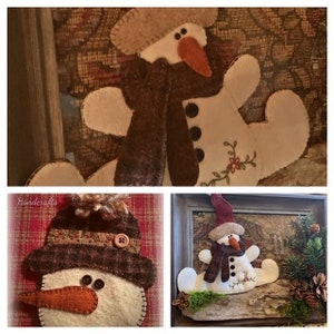 May include: Three felt snowman ornaments, each with a different style. The first snowman is wearing a brown hat and scarf, the second is wearing a brown hat and scarf and has a brown button nose, and the third is wearing a red hat and scarf and is sitting on a piece of driftwood.