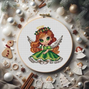 May include: A cross-stitch pattern of a Christmas angel with a green dress, red hair, and a halo. The angel is surrounded by a white background and a wreath of holly.