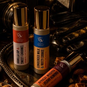 May include: Three perfume bottles with gold caps and labels in red, blue, and orange. The labels read "Vanilla Sip & Sweet Caramel", "Condensed Milk & Nutty Cookie", and "Apricot Whisper & Peony Almond". The bottles are on a silver tray with nuts and candies.