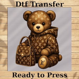 May include: A brown teddy bear wearing a brown hoodie and holding a matching handbag, both featuring a repeating pattern of logos. The bear has a gold logo on its foot. The text "Dtf Transfer" and "Ready to Press" are at the top and bottom.