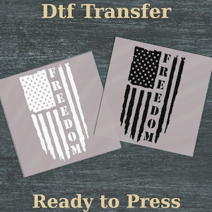 May include: Two gray transfer sheets with an American flag design and the word "FREEDOM" in white. One flag is white, the other is black. The text "Dtf Transfer" and "Ready to Press" are also visible.