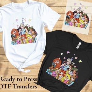 以下が含まれることがあります： 漫画のプリンセスが描かれたカラフルなグラフィックの白と黒のTシャツ。同じプリンセスのグラフィックが描かれた木の板も表示されています。「Ready to Press DTF Transfers」というテキストが画像の下部に印刷されています。