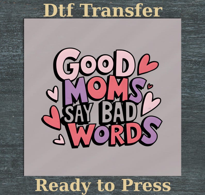 Puede incluir: Transferencia DTF gris con el texto "Good Moms Say Bad Words" en rosa, morado y negro, con detalles de corazones. Las palabras "Ready to Press" est&aacute;n en la parte inferior.