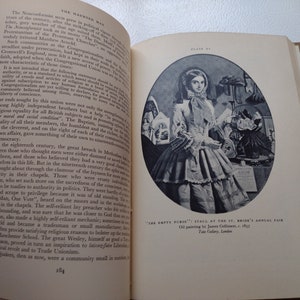 May include: Open book with text and a black and white illustration of a woman in a dress. The illustration is an oil painting titled "The Empty Purse" from 1857. The book is on a light-colored surface.
