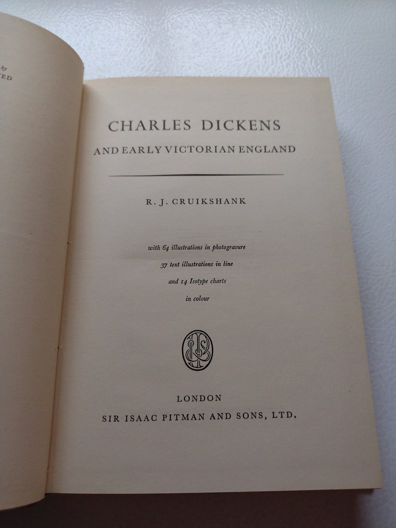May include: Open book titled "CHARLES DICKENS AND EARLY VICTORIAN ENGLAND" by R.J. Cruikshank. The book includes 64 illustrations in photogravure, 37 text illustrations in line, and 14 Isotype charts in color. Published by Sir Isaac Pitman and Sons, Ltd. in London.