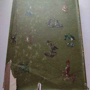 May include: Vintage book cover with a distressed green background and whimsical illustrations in black and red. The cover features various figures, including people on swings and in carriages, with some damage to the edges.