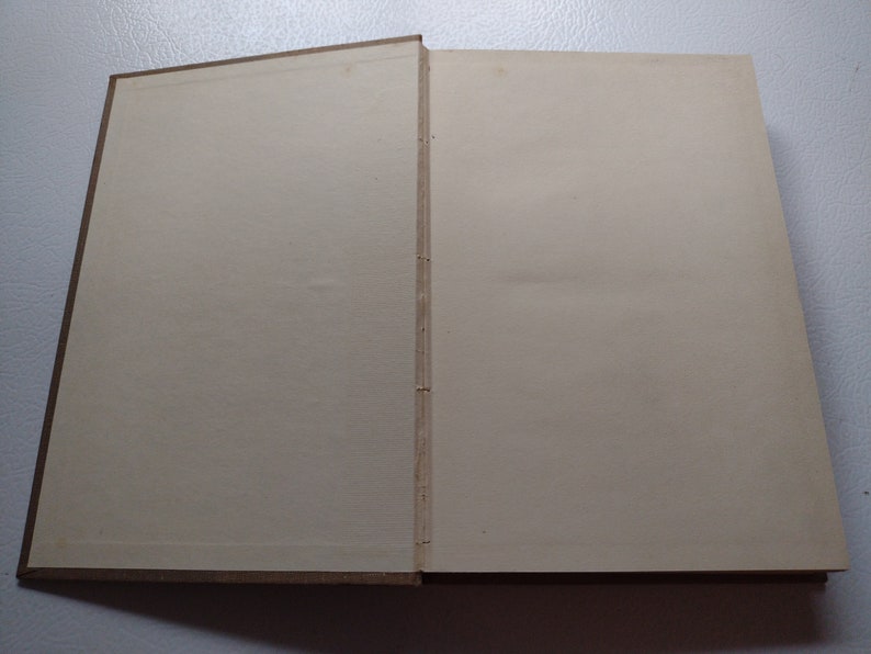 May include: An open book with a brown cover and off-white pages. The binding is visible, showing the stitching that holds the pages together. The pages are blank and ready for writing or reading.