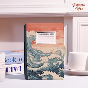 May include: Composition book featuring a stylized wave design in shades of blue and white against a peach and orange sky. The cover has the words "COMPOSITION BOOK" in a white rectangle.