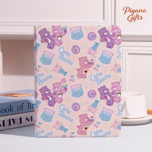 May include: A pink tablet case with a repeating pattern of Care Bears, lollipops, ice cream, cherries, and the text "Historic Route CB." The case has a smooth finish and a rectangular shape.
