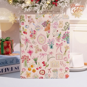 Può includere: Una confezione regalo decorativa con sfondo rosa chiaro e un motivo di illustrazioni floreali, orsacchiotti e altri disegni stravaganti. La scatola è rettangolare e in posizione verticale, con il testo "Piyana Gifts" visibile in alto a destra.