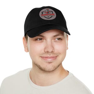 May include: A black baseball cap with a gray and red patch featuring a muscular figure and the text "Triumphs Divine Can't Beat What You've Already Built".