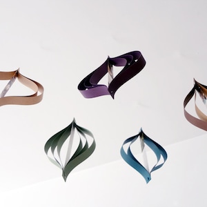 May include: Five paper ornaments in different colors, including brown, purple, green, and blue. The ornaments are made of folded paper and have a unique, teardrop shape.