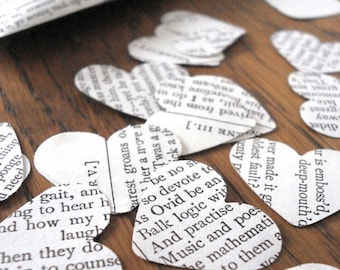 May include: White paper hearts with black text printed on them. The text is from a book and includes the words "gait, an", "rarest groans", "so devote to", "Balk logic", "And practise", "Music and poes", "is emboss'd", "deep-mouth'd", "oldest", "fault?", "to them a", "and see him", "That done", "ch", "your", "at this", "ou here", "Marre".