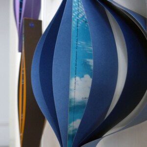 May include: A blue and white paper sculpture of clouds with vertical development. The text "Clouds with vertical development - Cumulonimbus Nimbus" is printed on the sculpture.