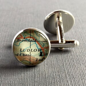 May include: Silver cufflinks with a glass dome featuring a vintage map of Ludlow, England. The map shows the town of Ludlow and surrounding areas, including Bromfield and Ludford Chase.
