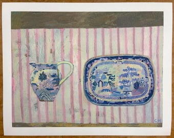 May include: A blue and white ceramic pitcher and a matching platter with a floral design are displayed on a pink and white striped surface.