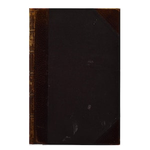 Peut inclure: Un livre à couverture rigide rectangulaire doté d'un dos et de coins en cuir texturé marron foncé contrastant avec un matériau de couverture noir lisse. Le dos présente des bandes verticales en relief et des lettres dorées estompées.