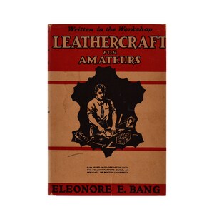 Puede incluir: Un libro titulado "Leathercraft for Amateurs" escrito en el taller por Eleonore E. Bang. La portada del libro presenta una ilustración en blanco y negro de una persona trabajando el cuero.