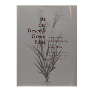 Puede incluir: Un libro titulado "At the Desert's Green Edge" con texto y una ilustración botánica. La portada es de color gris claro con texto marrón oscuro y un dibujo detallado de plantas del desierto.