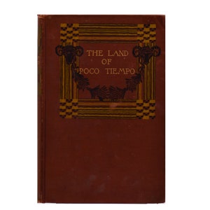 Könnte beinhalten: Der Einband eines Buches mit dem Titel "The Land of Poco Tiempo" mit einem dekorativen Rahmen und Illustrationen von Widderköpfen.