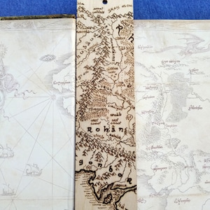 May include: A wooden bookmark with a laser-engraved map of Rohan from The Lord of the Rings. The map includes the text "Fangorn", "Westmark", "Eastmark", "Rohan", "Lothlórien", and "Harondor".
