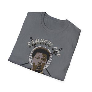 May include: A dark gray t-shirt with a graphic of a man with a surprised expression. The graphic is surrounded by swords and the text "SAMURAI COP".