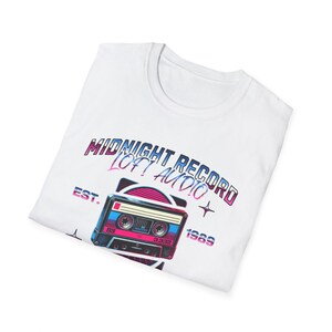 May include: White t-shirt with a graphic design of a cassette tape and the text "Midnight Record Loft Audio Est. 1989".
