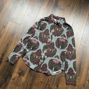 May include: A long-sleeved button-down shirt with a gray background and a repeating pattern of dark red and green floral designs. The shirt has a collared neckline and gold-colored buttons.