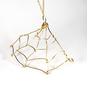 May include: A gold-toned necklace with a wire-wrapped spiderweb pendant.