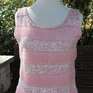 Puede incluir: Una blusa rosa sin mangas con un diseño de lentejuelas. Las lentejuelas están dispuestas en rayas horizontales.