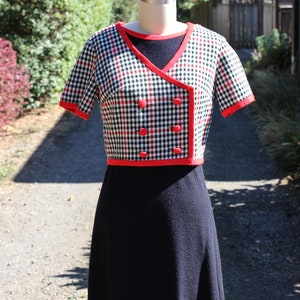 May include: A black and white gingham dress with red trim and buttons. The dress has a short-sleeved top and a knee-length skirt.
