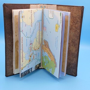 Könnte beinhalten: Ein handgefertigtes Notizbuch mit braunem Ledercover und Seiten mit Vintage-Karten. Das Notizbuch ist geöffnet und zeigt detaillierte Kartografie verschiedener Regionen. Natürliches Bindegarn hält die Seiten zusammen und erzeugt eine einzigartige, rustikale Ästhetik.