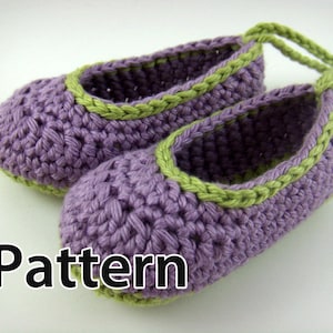 Pode incluir: Sapatinhos de bebé em crochê roxo e verde com um laço no topo. Padrão.