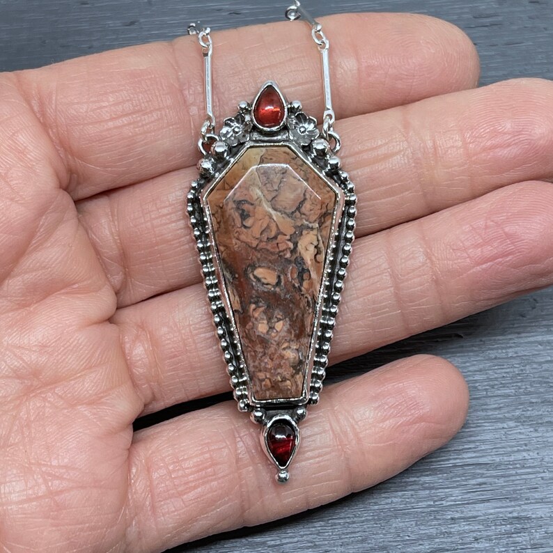 coffin shaped gemstone pendant with two garnet stones