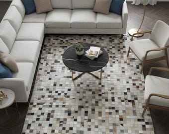 May include: A contemporary living room with a light grey corner sofa, blue and beige cushions, a black marble coffee table, and two armchairs. The floor is covered by a mosaic patterned rug. The text "ECLATIQUE RUG" is visible.
