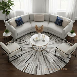 Peut inclure: Aménagement de salon moderne avec un canapé gris clair incurvé, des coussins décoratifs, une table basse ronde en marbre et un tapis à motifs. Deux chaises blanches avec des cadres noirs et de petites tables d'appoint complètent l'ensemble.