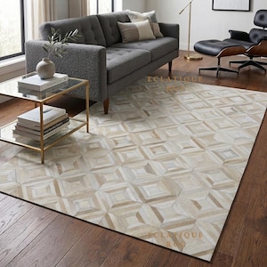 May include: A rectangular area rug featuring a geometric pattern composed of light beige, cream, and white leather tiles. The rug displays a repeating square and diamond motif across its surface, with the text ECLATIQUE RUG visible on the floor.