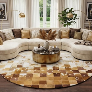 Peut inclure: Un canapé sectionnel incurvé de couleur crème avec des coussins décoratifs bruns et dorés. Un tapis rond à motifs bruns et crème est placé sous une table basse dorée. Deux lampes dorées en arc illuminent la pièce.