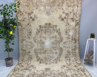 May include: A large rectangular area rug featuring a faded beige background with intricate dark brown floral and scrollwork patterns. The design includes a prominent central medallion surrounded by elaborate botanical motifs and decorative borders.