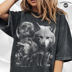 Peut inclure: Un t-shirt gris anthracite à manches courtes avec une impression graphique représentant plusieurs loups et une grande pleine lune. Le t-shirt porte le texte Comfort Colors Pepper dans le coin supérieur droit et a une coupe ample.