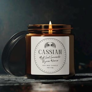 Peut inclure: Un bocal en verre brun contenant une bougie avec une étiquette blanche. L'étiquette présente une illustration en noir et blanc d'une créature ailée et le texte "Cassian Night Court Commander Illyrian Warrior Soy Wax Candle 4 oz/113g".
