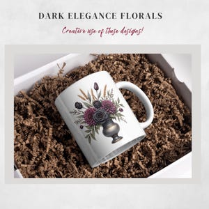 May include: White ceramic mug featuring a floral design with dark purple and gray flowers, wheat stalks, and green leaves. The mug is inside a white box filled with brown shredded paper. The text "DARK ELEGANCE FLORALS" and "Creative use of these designs!" are at the top.