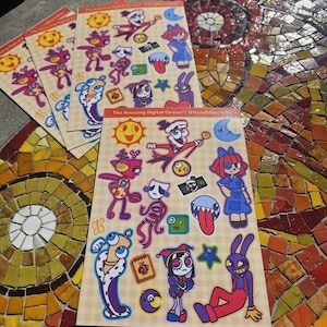 May include: Several sticker sheets featuring colorful cartoon characters and the text "The Amazing Digital Circus!! @DeadManWife". The stickers include various whimsical designs, such as a sun, moon, and a jester.