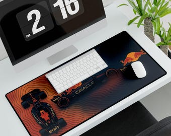 May include: A black and red desk mat featuring a Formula 1 race car design with the Oracle and Bybit logos. The mat has a gradient background with a white keyboard and mouse on top. A computer monitor displays the time.