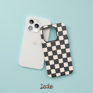 Puede incluir: Un smartphone blanco con una funda a cuadros negros y crema. La funda del teléfono está junto al teléfono sobre una superficie azul claro. La funda del teléfono tiene un patrón cuadrado. El teléfono tiene tres lentes de cámara.