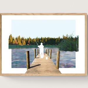 May include: A framed print featuring a serene lake scene. A silhouetted figure fishes from a wooden pier extending into the water. The background shows a forest and a clear sky, creating a peaceful outdoor setting.