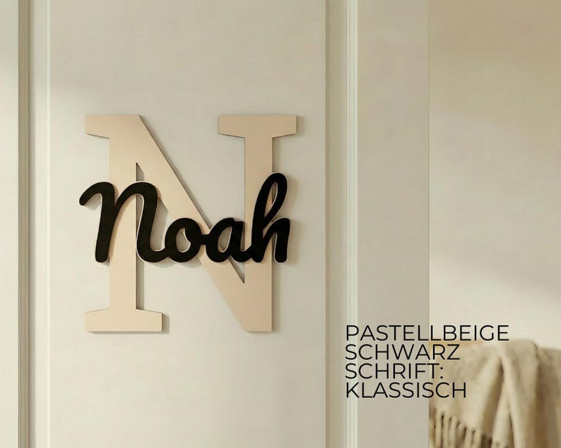 May include: A wooden wall decoration featuring the name "Noah" in black script over a large, light beige letter "N". The background is a light beige wall. The text on the right says "Pastellbeige, Schwarz, Schrift: Klassisch."