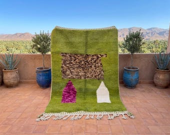 May include: A rectangular area rug featuring a vibrant lime green base color. The center displays a large, textured brown rectangular patch. Below this, two smaller shapes are present: one in magenta and one in white. The rug has tasseled edges.