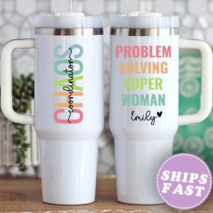 May include: Two white insulated tumblers with handles. One reads "Chaos Coordinator" in colorful text. The other says "Problem Solving Super Woman Emily" with a heart. A purple sticker says "Ships Fast".