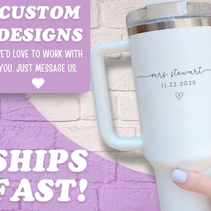 May include: White insulated tumbler with a handle, featuring the text "mrs. stewart" and the date 11.22.2026, along with a heart symbol. The tumbler has a clear lid and is held by a person. The image also includes text that says "CUSTOM DESIGNS" and "SHIPS FAST!"